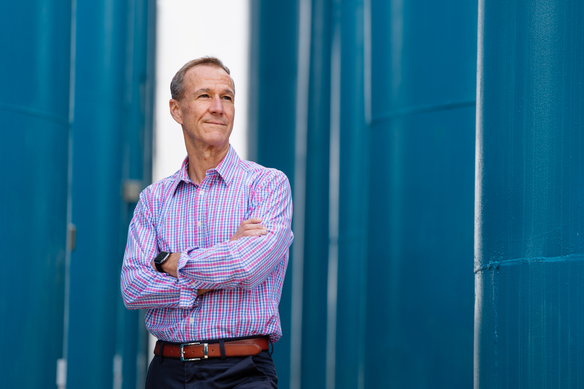 Tim Hutchens, owner of Hutchens Rentz-Eden standing in front of large blue tanks, posing for photo.