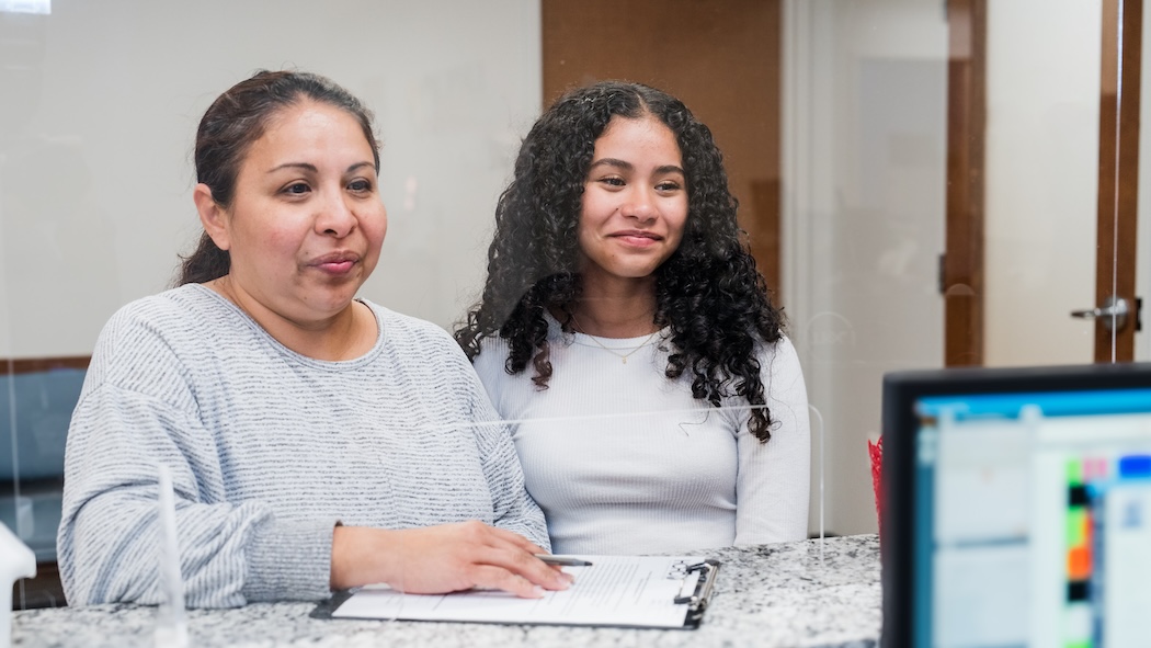 Two women standing on the other side of a partition at HCHC's clinic