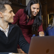 Female training instructor discussing training materials with two attendees who are seated on their laptops.