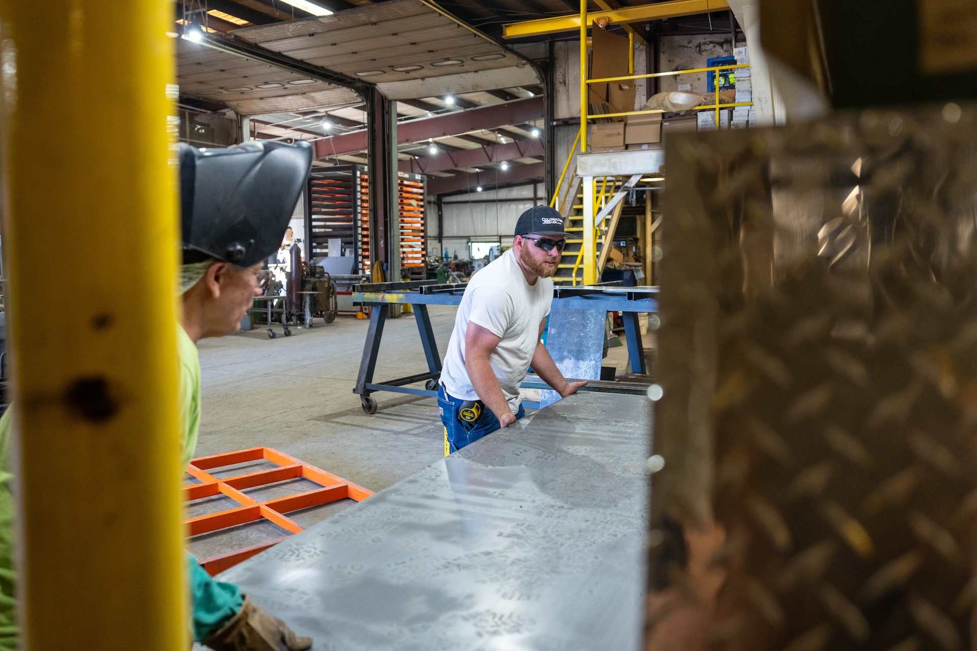 Employee inside a warehouse moving large sheet of metal material